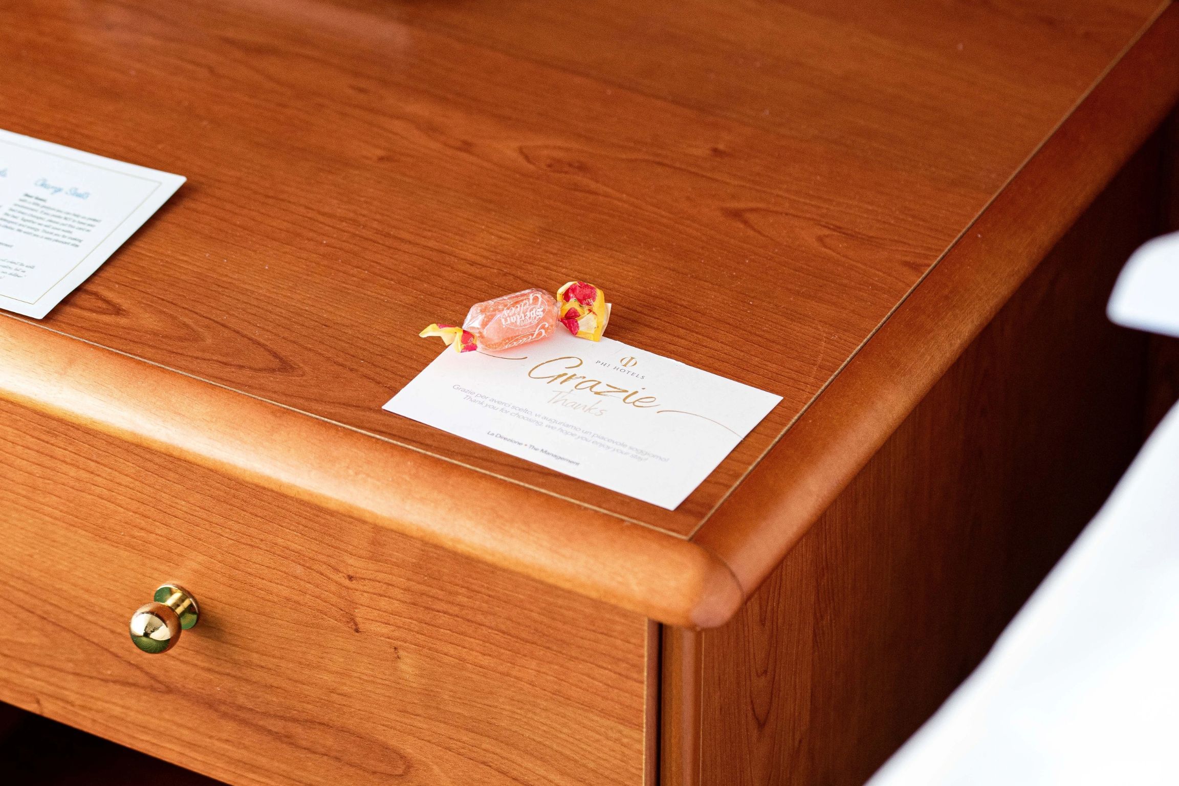 A wooden desk with a card and a wrapped item on it.