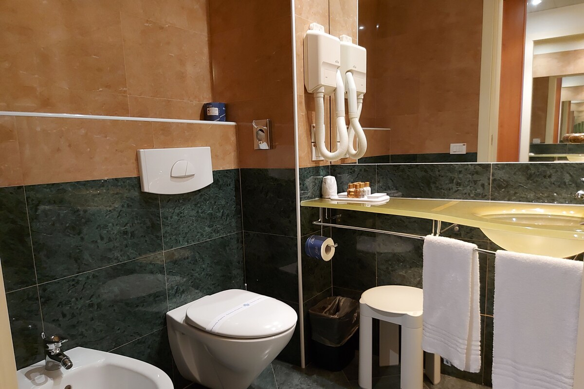 Une salle de bain moderne équipée d’un bidet, de toilettes, d’un lavabo et d’un miroir.