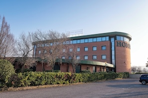 A hotel with a curved facade, multiple windows, and a sign indicating it is part of the PHI HOTELS chain.