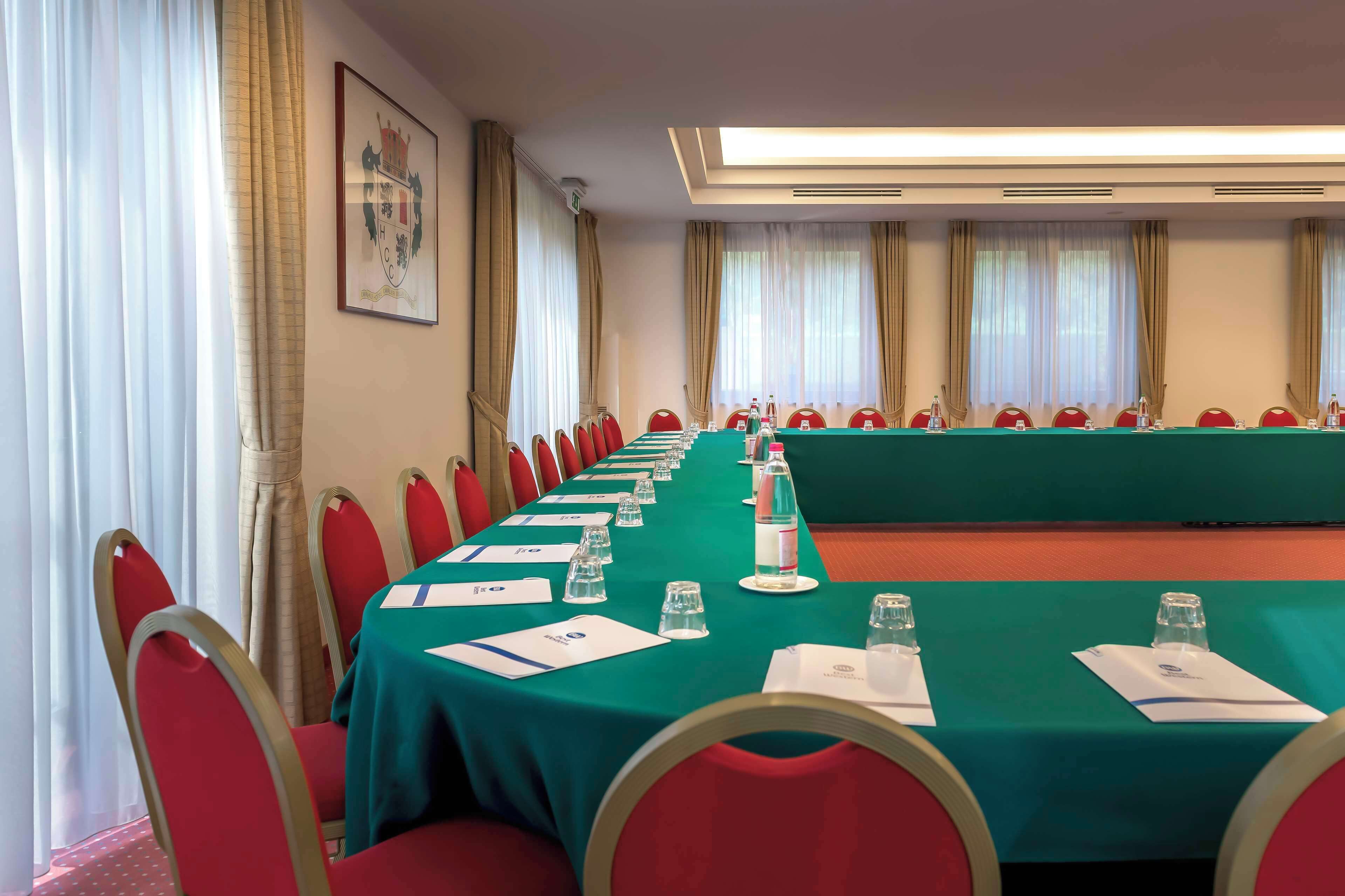 A conference room with a long table, red chairs, and a green tablecloth.