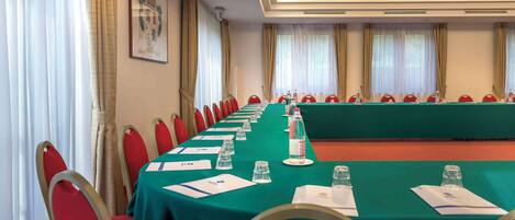 A conference room with a long table, red chairs, and a green tablecloth.