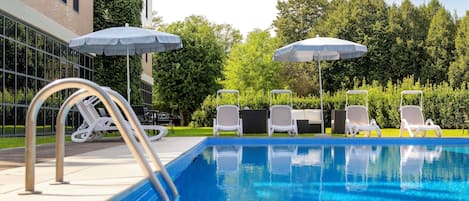 Una piscina al aire libre de temporada, sombrillas, tumbonas