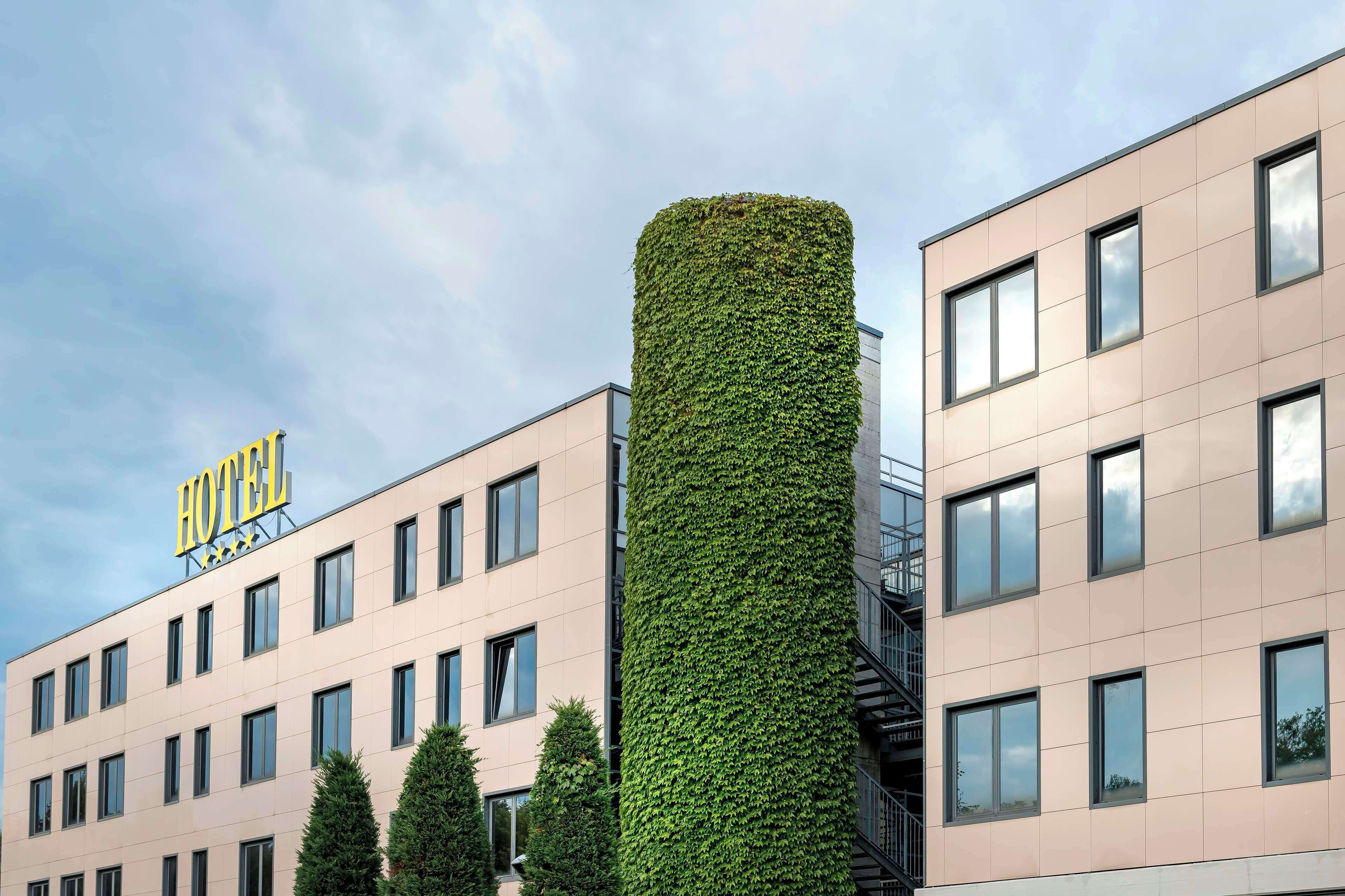 Un hotel con fachada moderna y un destacado jardín vertical, con un cartel que indica que es un hotel.