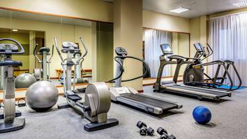 A hotel gym with various exercise equipment including treadmills, elliptical machines, and free weights.