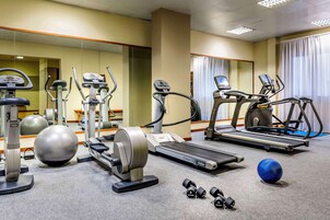 A hotel gym with various exercise equipment including treadmills, elliptical machines, and free weights.