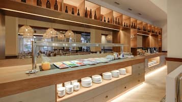 Zona de bufé con diversas opciones de comida, un botellero y una estación de café.