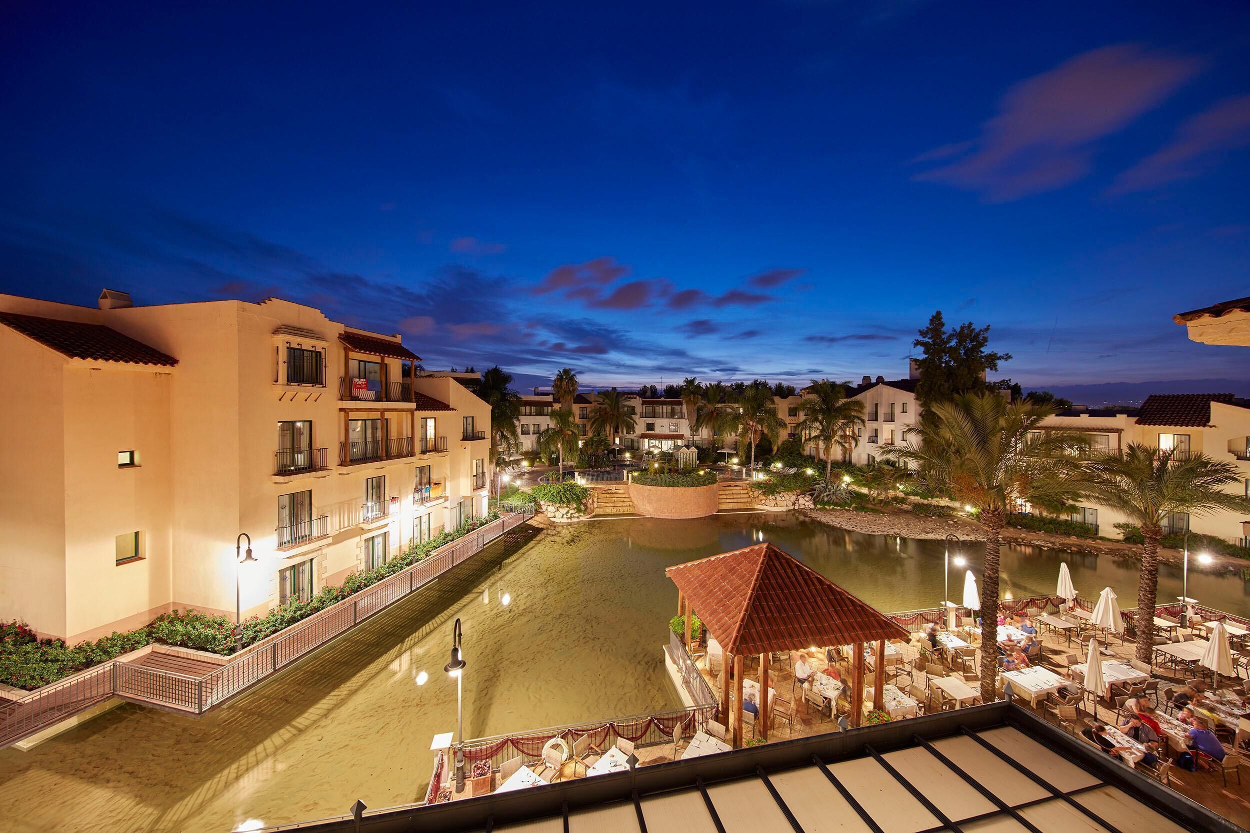 Un patio de hotel con piscina, asientos al aire libre y vistas de edificios circundantes.
