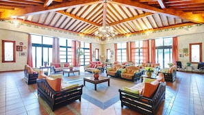 Un vestíbulo amplio con vigas de madera, ventanas grandes y zonas de estar cómodas.