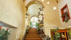 A grand staircase with ornate railings, leading to a balcony adorned with potted plants and flowers. - PortAventura Hotel El Paso - Includes unlimited access to PortAventura Park & 1 day access to Ferrari Land (Salou)
