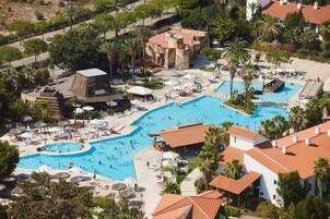 A resort with multiple swimming pools, sun loungers, and palm trees.