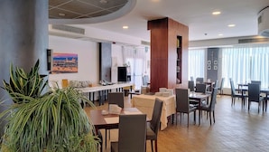 Un comedor moderno con techo alto, una columna central y un cuadro panorámico de la ciudad.