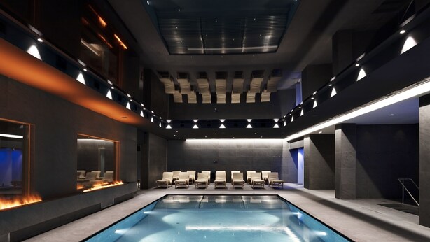 A modern indoor swimming pool with a long, narrow shape, surrounded by seating areas and a high ceiling with recessed lighting. - Grand Hotel Duca D'Este (Tivoli)