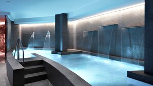 A modern spa area with a heated pool, multiple water features, and a staircase leading to the pool. - Grand Hotel Duca D'Este (Tivoli)
