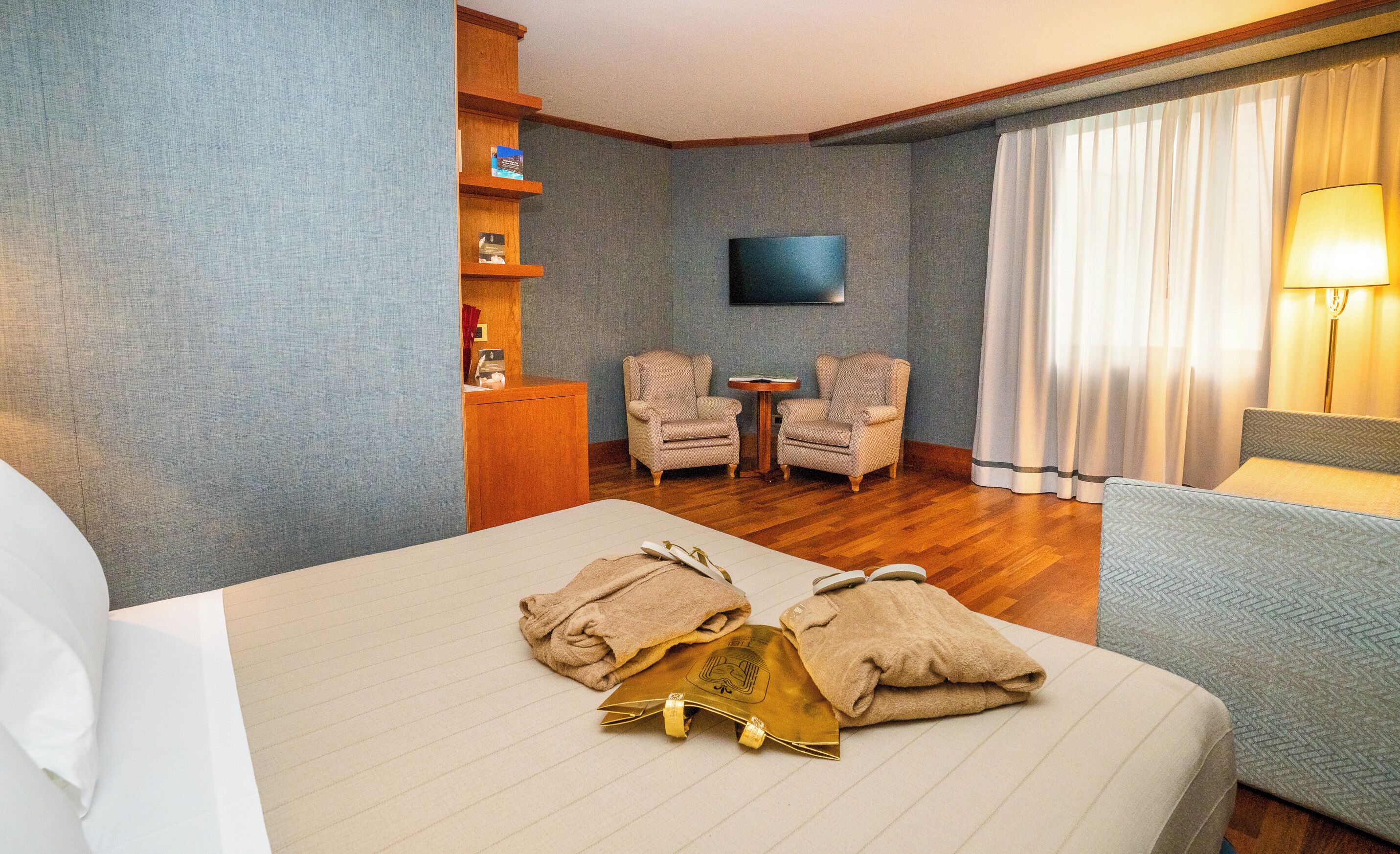 Habitación de hotel con cama, dos sillones, una mesita, televisor y lámpara.