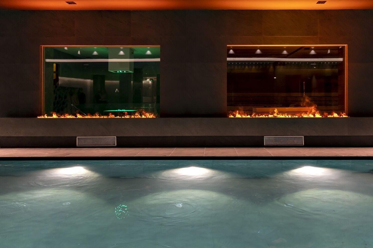 A swimming pool with a fire feature and a glass enclosure.