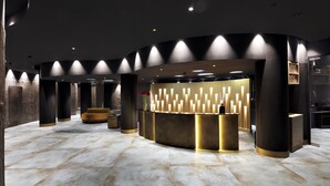 A reception area with a modern design, featuring a curved reception desk, large pillars, and a marble floor. - Grand Hotel Duca D'Este (Tivoli)