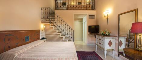 A bedroom with a bed, a desk, a dresser, a mirror, a staircase, and a balcony.