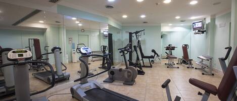 A gym with various exercise equipment including treadmills, elliptical machines, and weight machines.