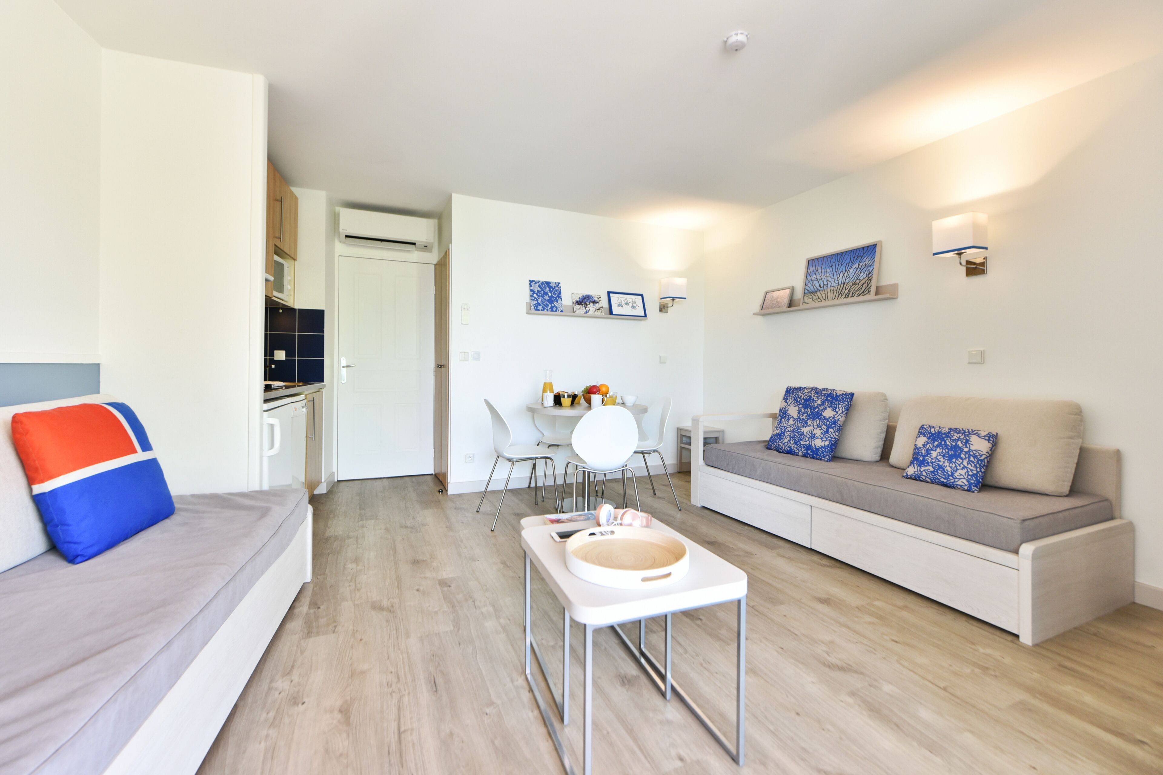 Un soggiorno moderno con un divano, un tavolo da pranzo con sedie e una zona cucina sullo sfondo.
