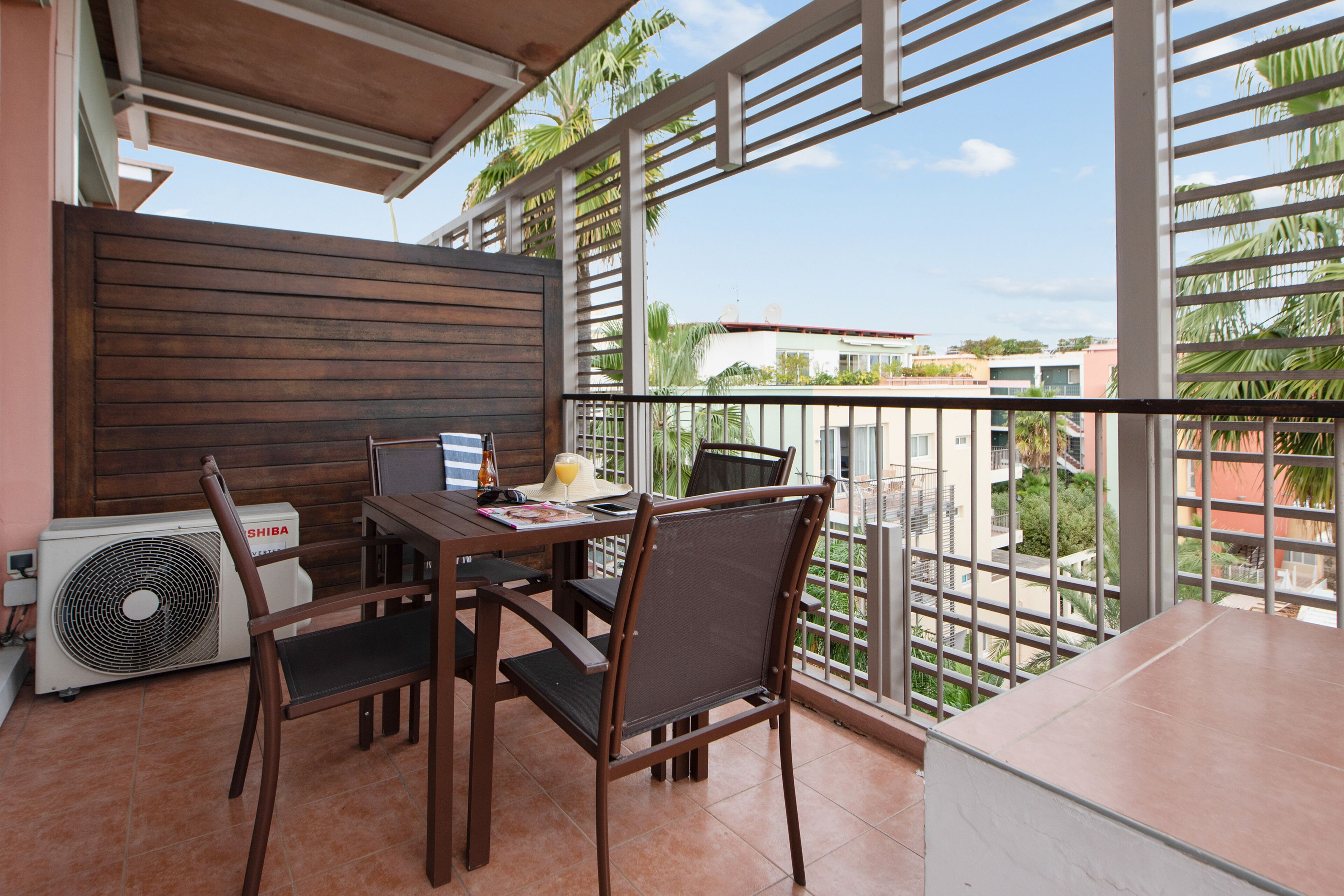 A balcony with a table, chairs, and a fan.