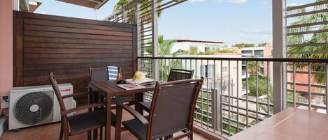 A balcony with a table, chairs, and a fan.