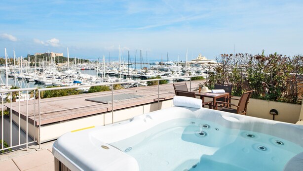 A rooftop terrace with a hot tub, overlooking a marina with numerous boats and a castle in the distance. - Résidence Pierre & Vacances Premium Port-Prestige (Antibes)