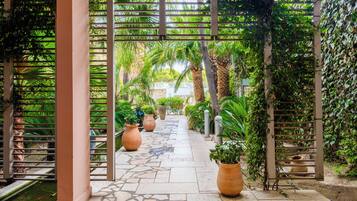 Un sendero bordeado de plantas en macetas y una estructura de pérgola.