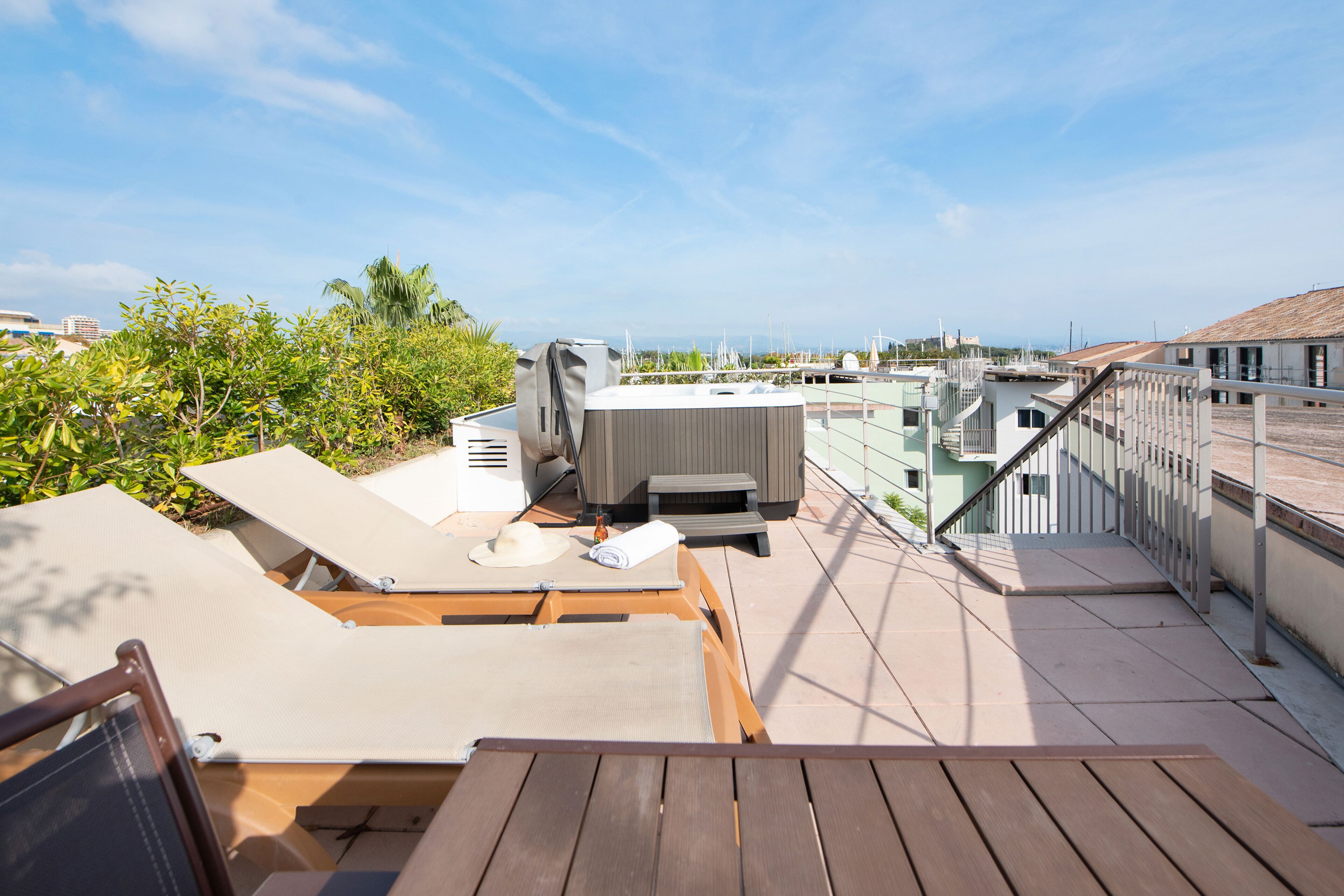 A rooftop terrace with lounge chairs, a barbecue grill, and a view of the cityscape.
