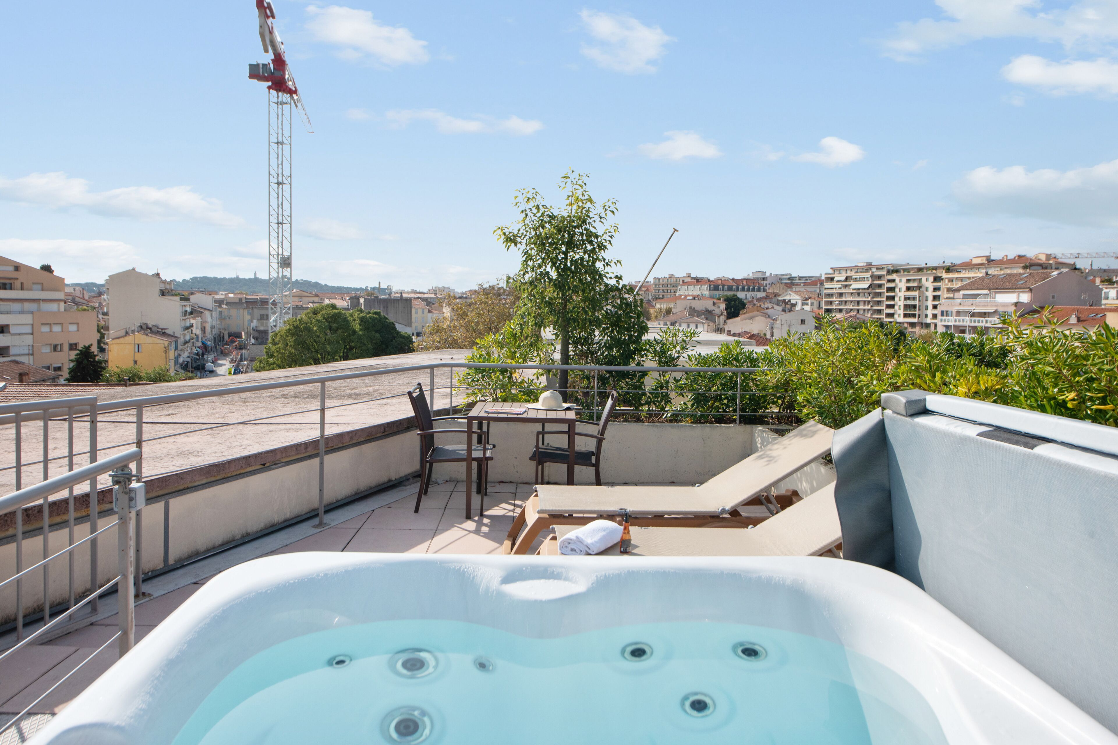 Une terrasse sur le toit avec un jacuzzi, des sièges extérieurs et une vue sur le paysage urbain.