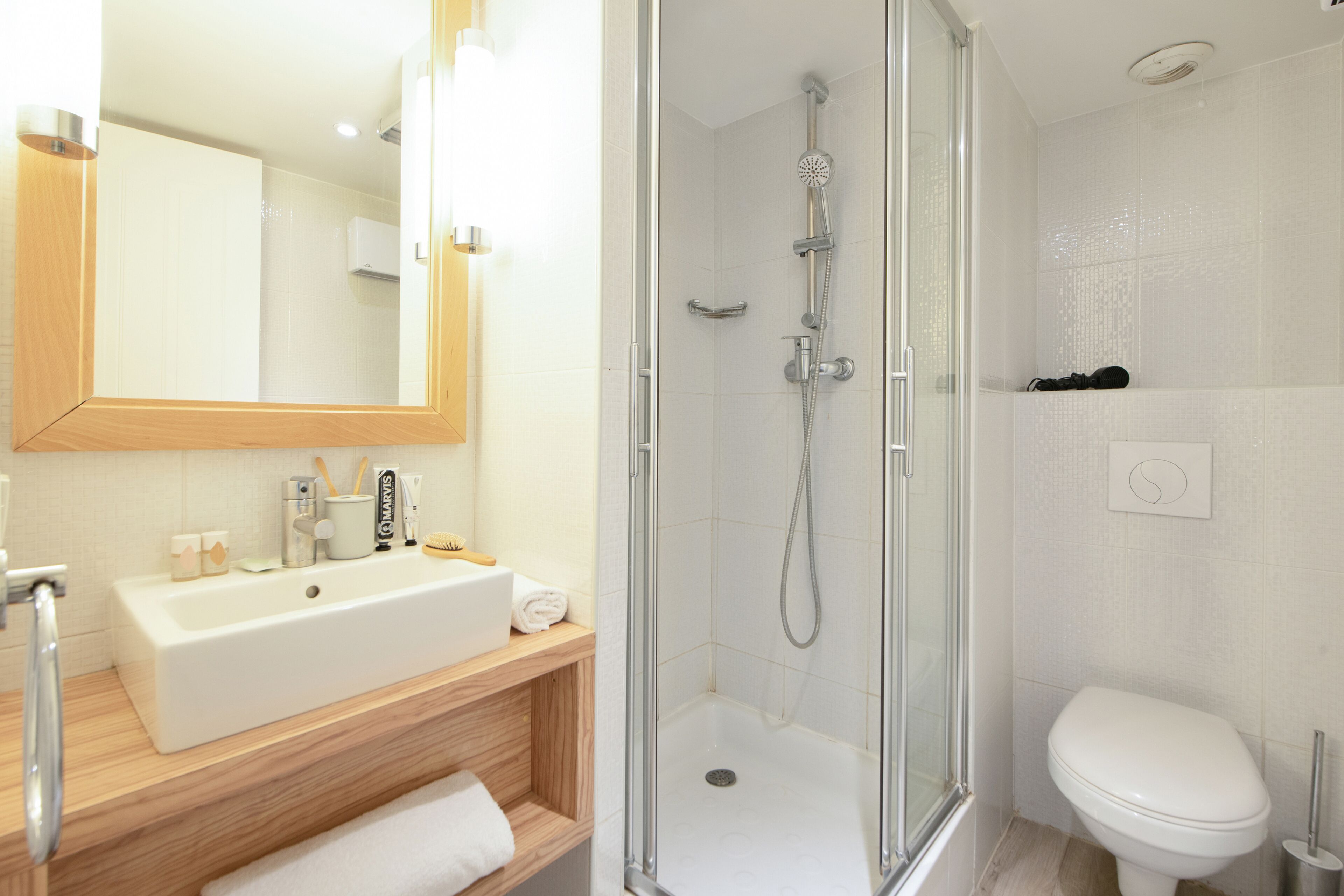 A modern bathroom with a glass-enclosed shower, a white sink, and a large mirror.