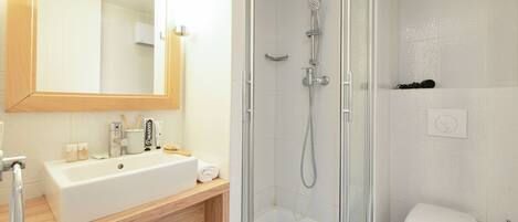 A modern bathroom with a glass-enclosed shower, a white sink, and a large mirror.