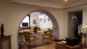 Una sala de estar con sofá, sillas, televisor y un arco decorativo.