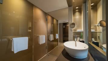 Une salle de bain moderne avec un grand lavabo blanc, une douche en verre et un miroir au-dessus du lavabo.