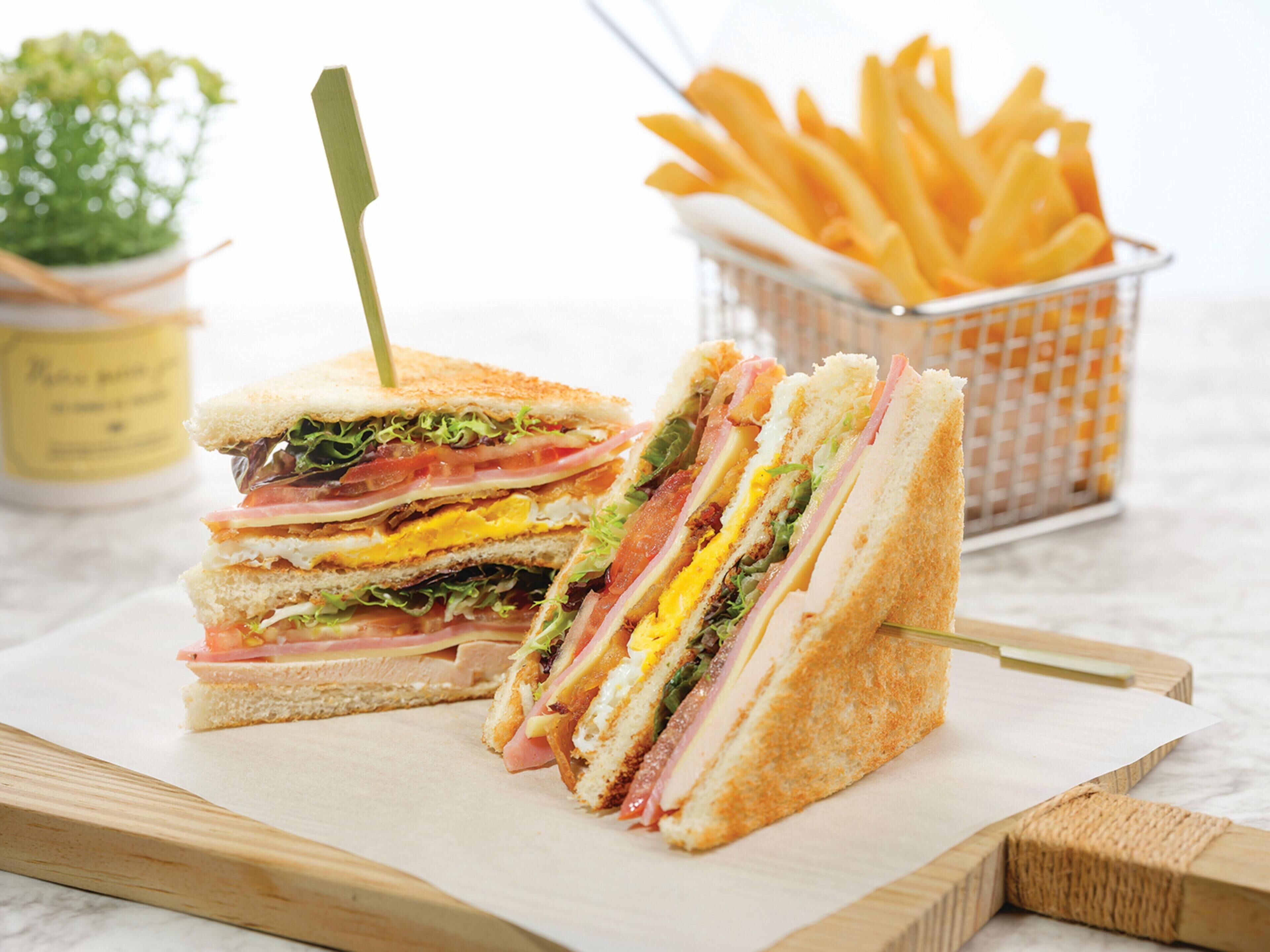 A sandwich cut in half with a toothpick, placed on a wooden board.