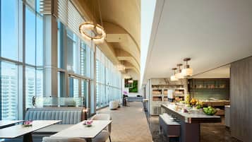 Eine moderne Hotelhalle mit einer langen Rezeption, einer Sitzecke und einer Küche im Hintergrund.