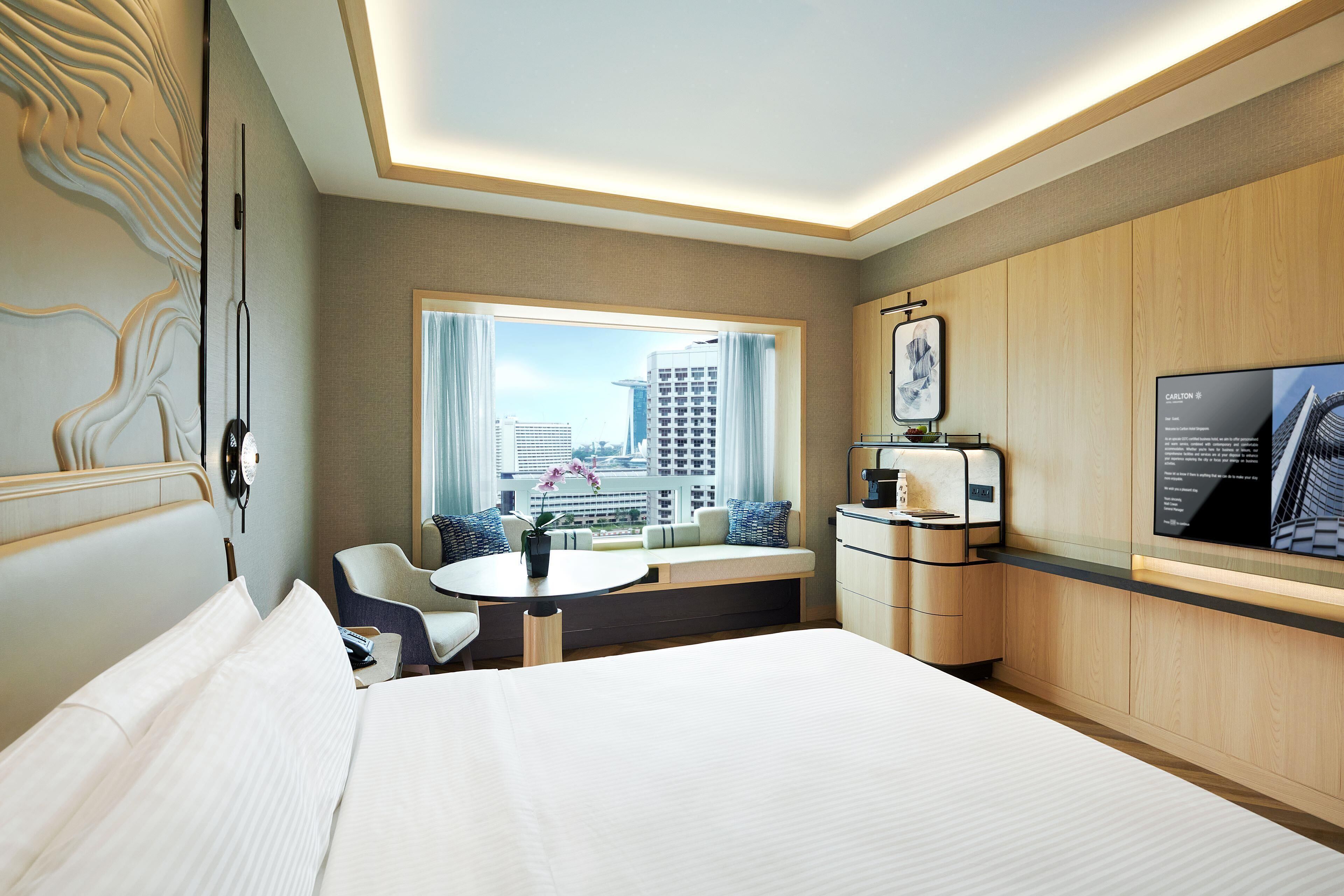 A hotel room with a bed, a desk, a chair, a coffee machine, and a television.