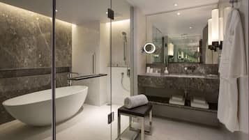 Un baño moderno con una bañera independiente, ducha con cerramiento de vidrio, tocador con espejo y un perchero para toallas.