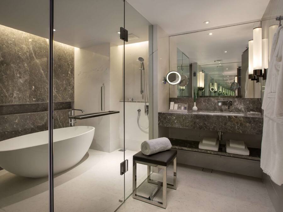 Une salle de bain moderne avec une baignoire sur pieds, une douche à parois de verre, un meuble-lavabo avec un miroir et un porte-serviettes.