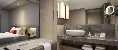 A modern bathroom with a large mirror, a bathtub, a sink, and a vanity.
