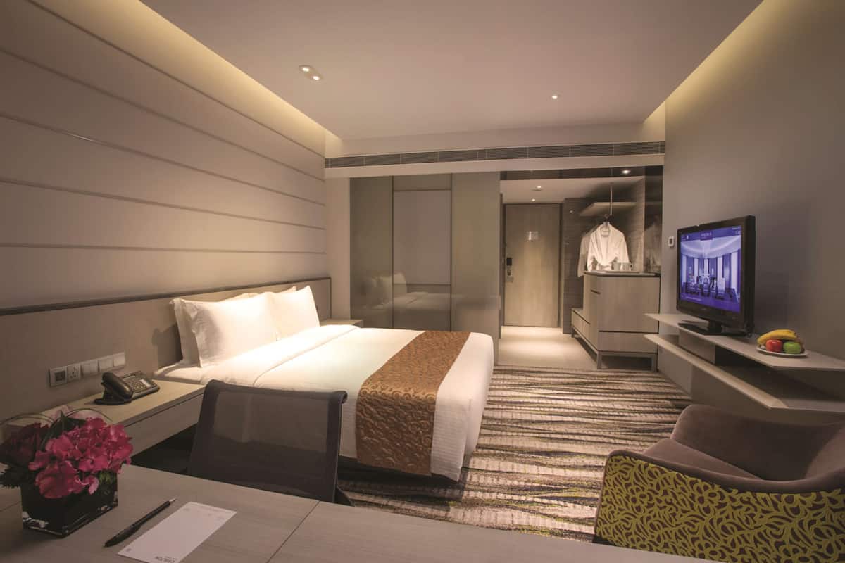 Une chambre d’hôtel équipée d’un lit, d’un bureau, d’une chaise, d’une télévision et d’un petit panier de fruits.