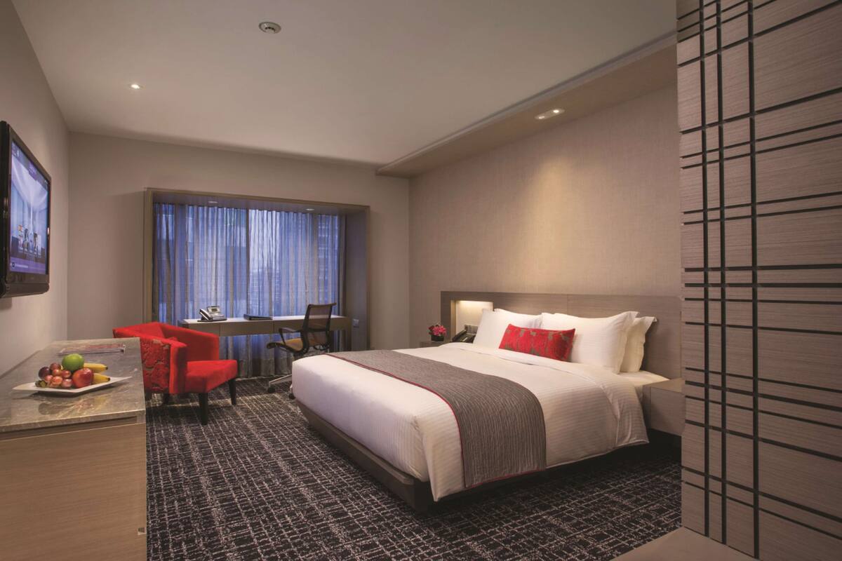 Een hotelkamer met een bed, een bureau, een stoel en een televisie.