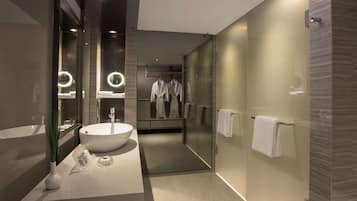 A modern bathroom with a large sink, mirror, and glass shower enclosure.