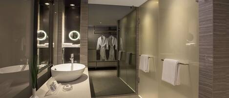 A modern bathroom with a large sink, mirror, and glass shower enclosure.