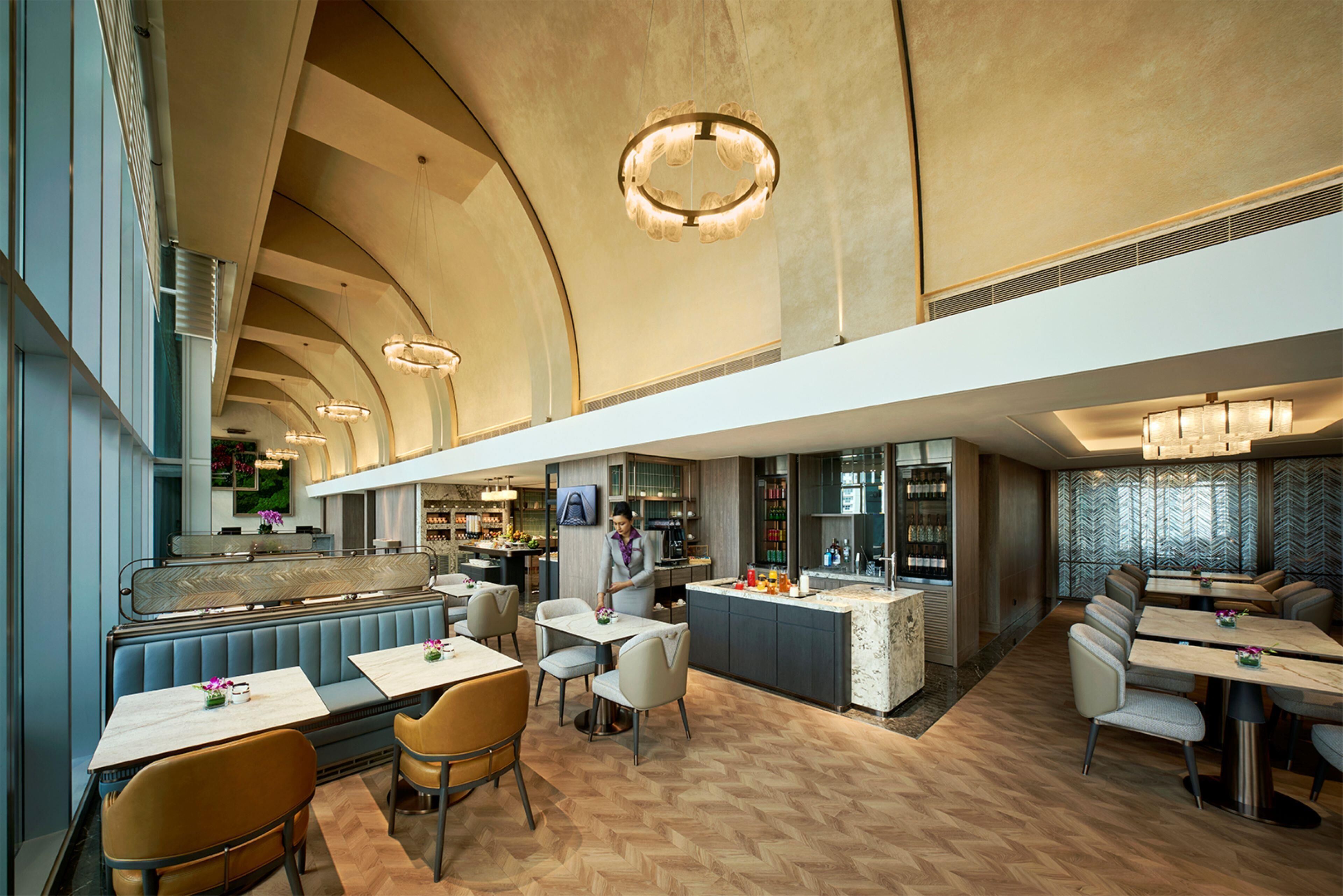 A spacious restaurant with a high ceiling, modern lighting fixtures, and a central bar area.