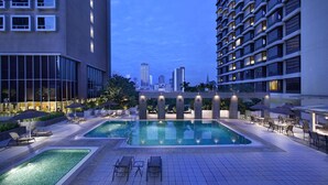 A rooftop pool with lounge chairs and umbrellas, surrounded by high-rise buildings. - Carlton Hotel Singapore (Singapore)