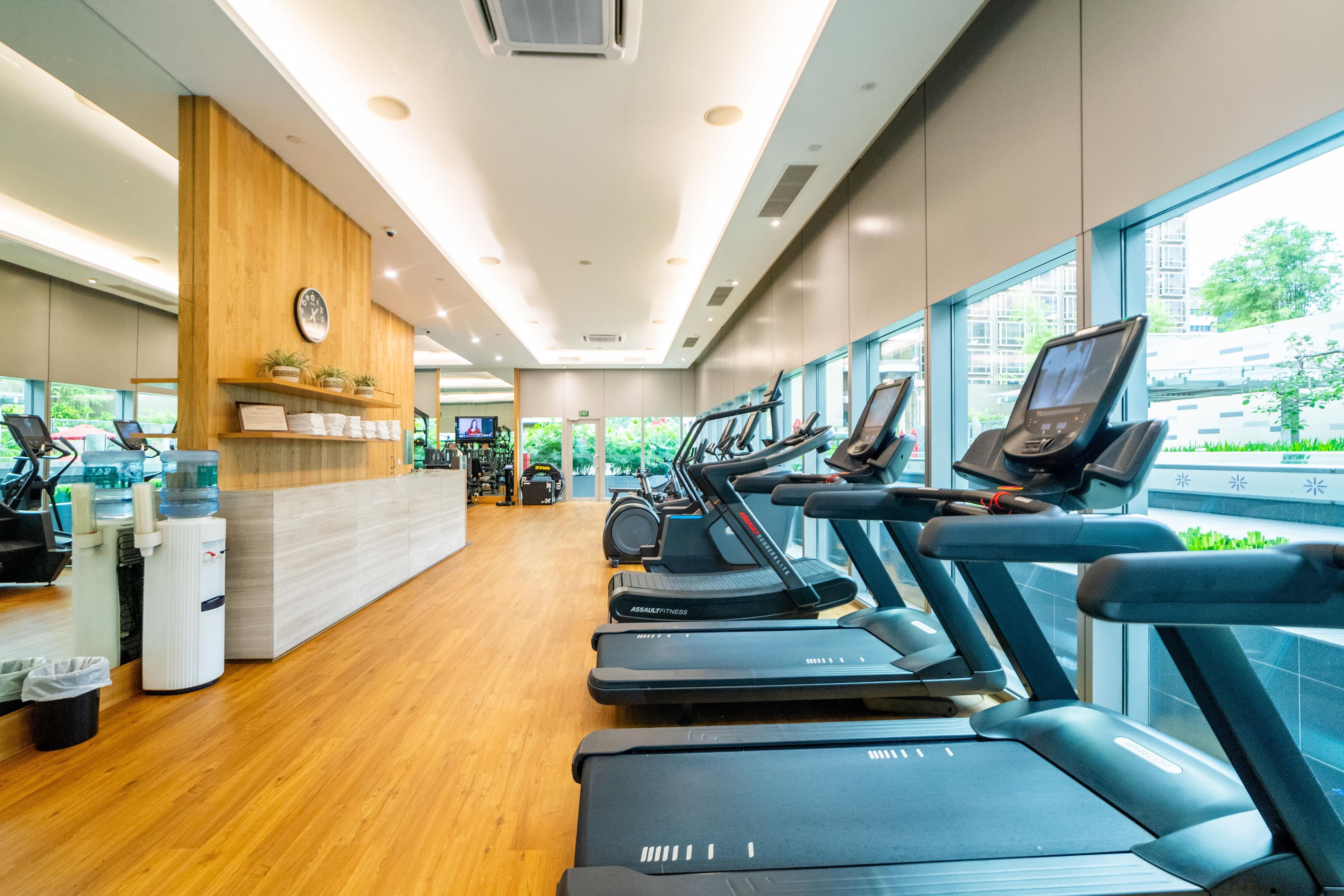 A gym with treadmills, exercise equipment, and a wooden reception desk.