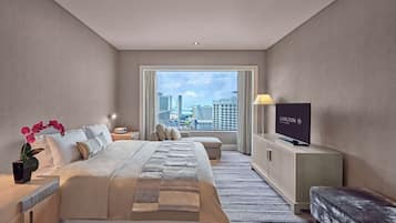 A hotel room with a bed, a TV, a desk, and a view of the city.