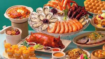 Una variedad de platos de mariscos, incluyendo ostras, camarones y un cerdo asado entero, dispuestos sobre una mesa.