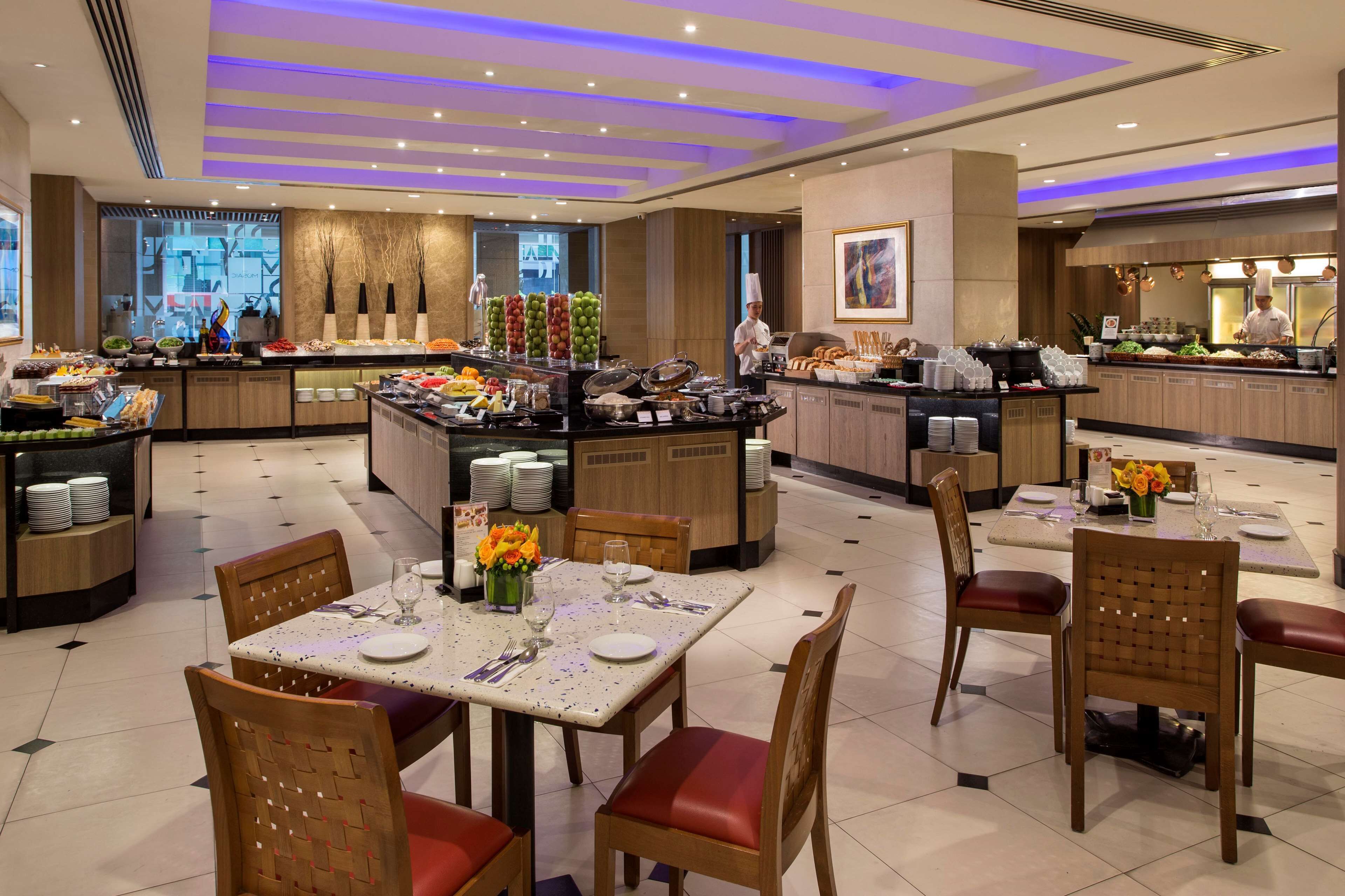 A hotel dining area with a buffet, multiple dining tables, and chairs.