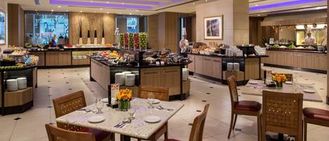 Ein Hotel-Speisesaal mit Buffet, mehreren Tischen und Stühlen.
